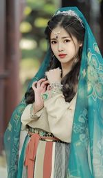 Portrait of young woman standing against blurred background