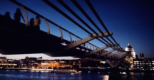 Illuminated bridge over river against sky at dusk