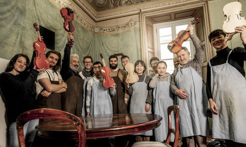 Group of people teachers and students violin maker while posing in a historic room