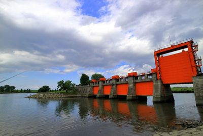 Red canal lock over lake against sky