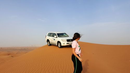 Man standing on sand dune in desert against sky