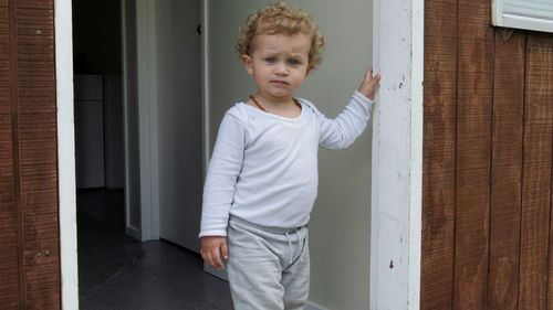 Portrait of boy standing at doorway of house