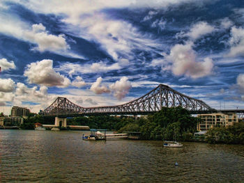 Bridge over river against cloudy sky