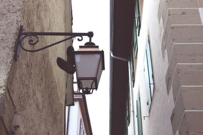 Low angle view of street light by buildings against sky