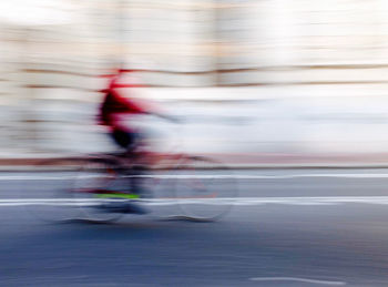 Blurred motion of person riding bicycle on road
