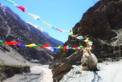 Low angle view of multi colored flags on rock against sky