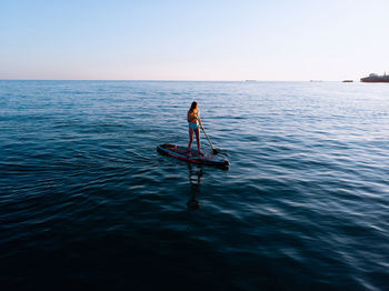 Full length of woman paddleboarding in sea