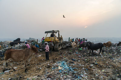 People on garbage against sky