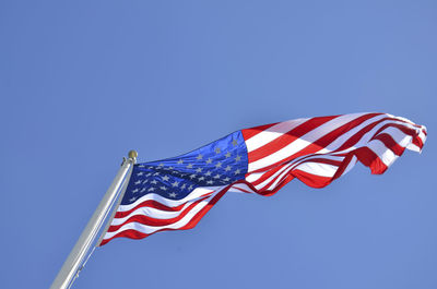 Low angle view of north american flag against clear blue sky