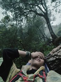 Headshot of man with head in hand while resting in forest