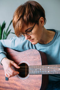 Woman with short hair enjoys playing guitar at home. music lessons for adults