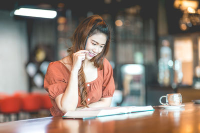 Midsection of woman with drink sitting in cafe