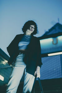 Low angle view of young woman standing against sky