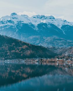 Scenic view of lake by snowcapped mountains against sky