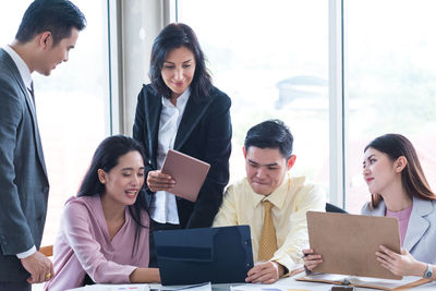 Smiling colleagues working on desk at office