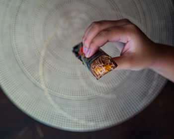 Cropped hand of man holding chocolate bar at home