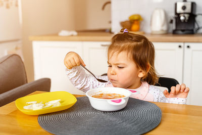 Cute girl eating food at table