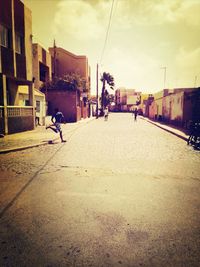 People walking on city street against sky