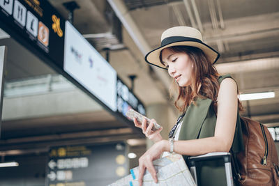 Woman using mobile phone while standing at airport terminal