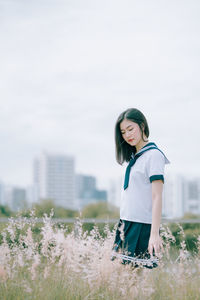 Young woman standing amidst plants on field