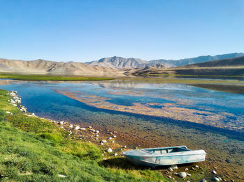 Scenic view of lake and mountains against clear blue sky