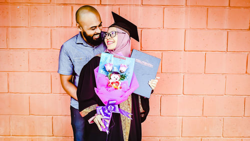 Couple standing against wall