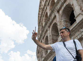 Low angle view of man holding umbrella against sky