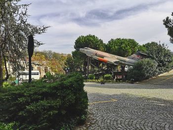 Road amidst plants and trees against sky in city