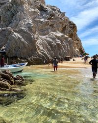 People on rock formations against sky