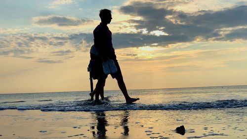 Man standing on beach against sky during sunset