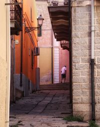 Rear view of people walking on footpath amidst buildings in city