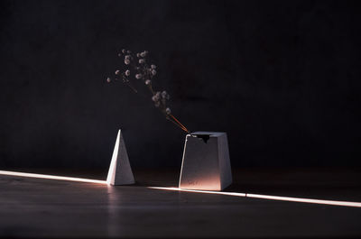 Close-up of smoke emitting from container on table against wall