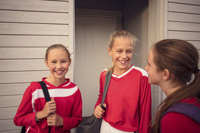 Happy girls talking while standing against wall