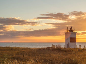 View of lighthouse on beach during sunset