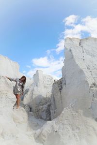 Low angle view of woman on white rock formation against sky