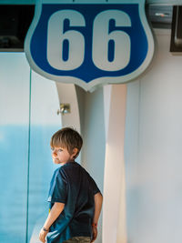 Boy standing against wall by door