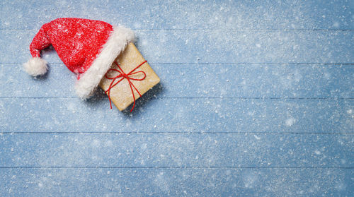 High angle view of gift with santa hat on table during snowfall