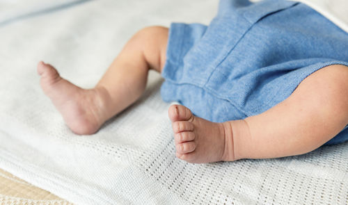 Low section of baby lying on bed