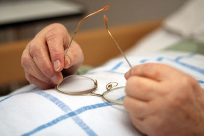 Cropped hands of senior person holding eyeglasses