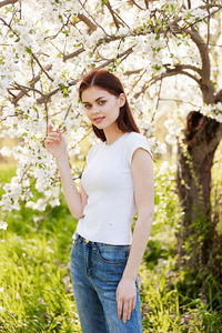 Young woman standing against plants