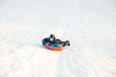 Full length of boy playing on snow outdoors