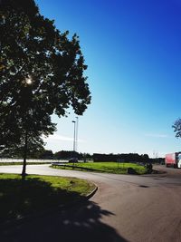 Road by trees in city against clear sky