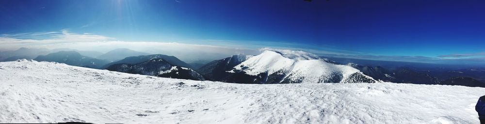 Scenic view of snowcapped mountains against blue sky