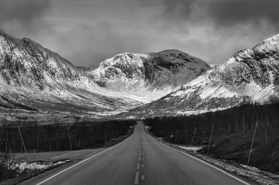 Road amidst snowcapped mountains against sky