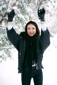 Portrait of smiling woman standing against snow