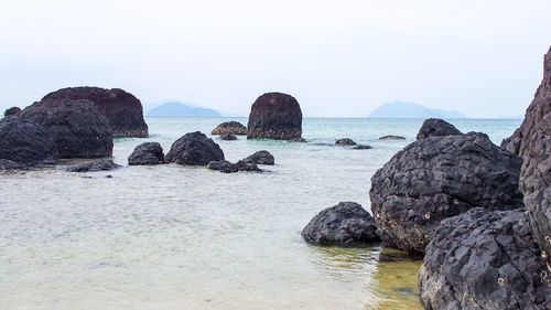 Rocks on beach against clear sky