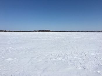 Scenic view of frozen lake against clear blue sky