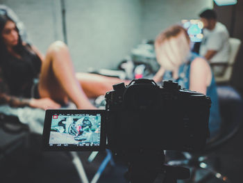 Close-up of camera filming tattooist making tattoo on customer leg in shop