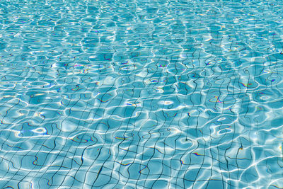 Sun reflection in blue water of swimming pool, shining blue water ripple, aqua texture, pattern