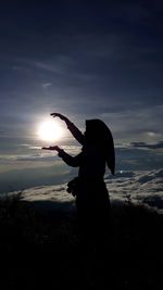 Silhouette woman standing at beach against sky during sunset